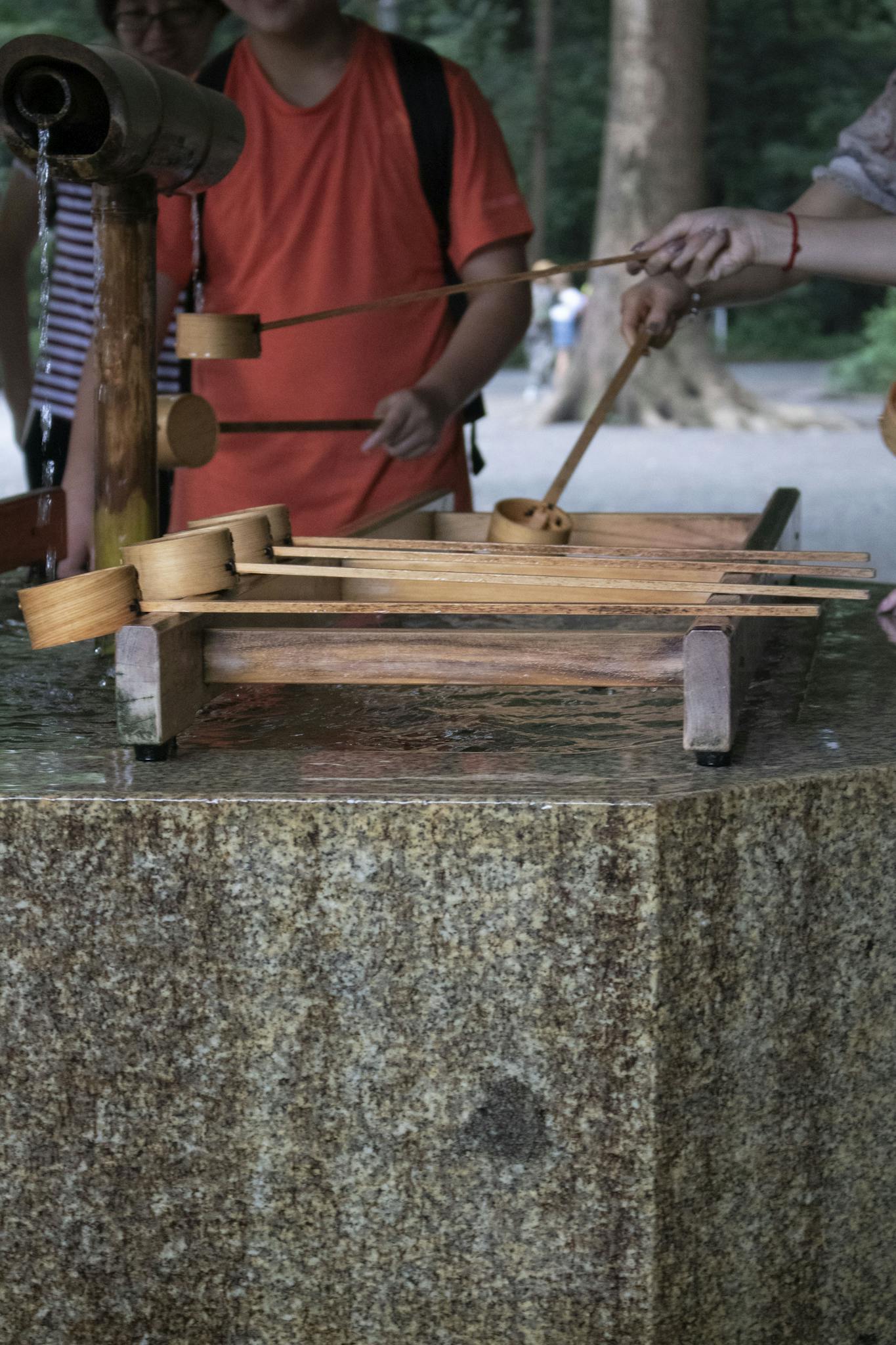 People performing a purification ritual at a Japanese Shinto shrine's chozuya.