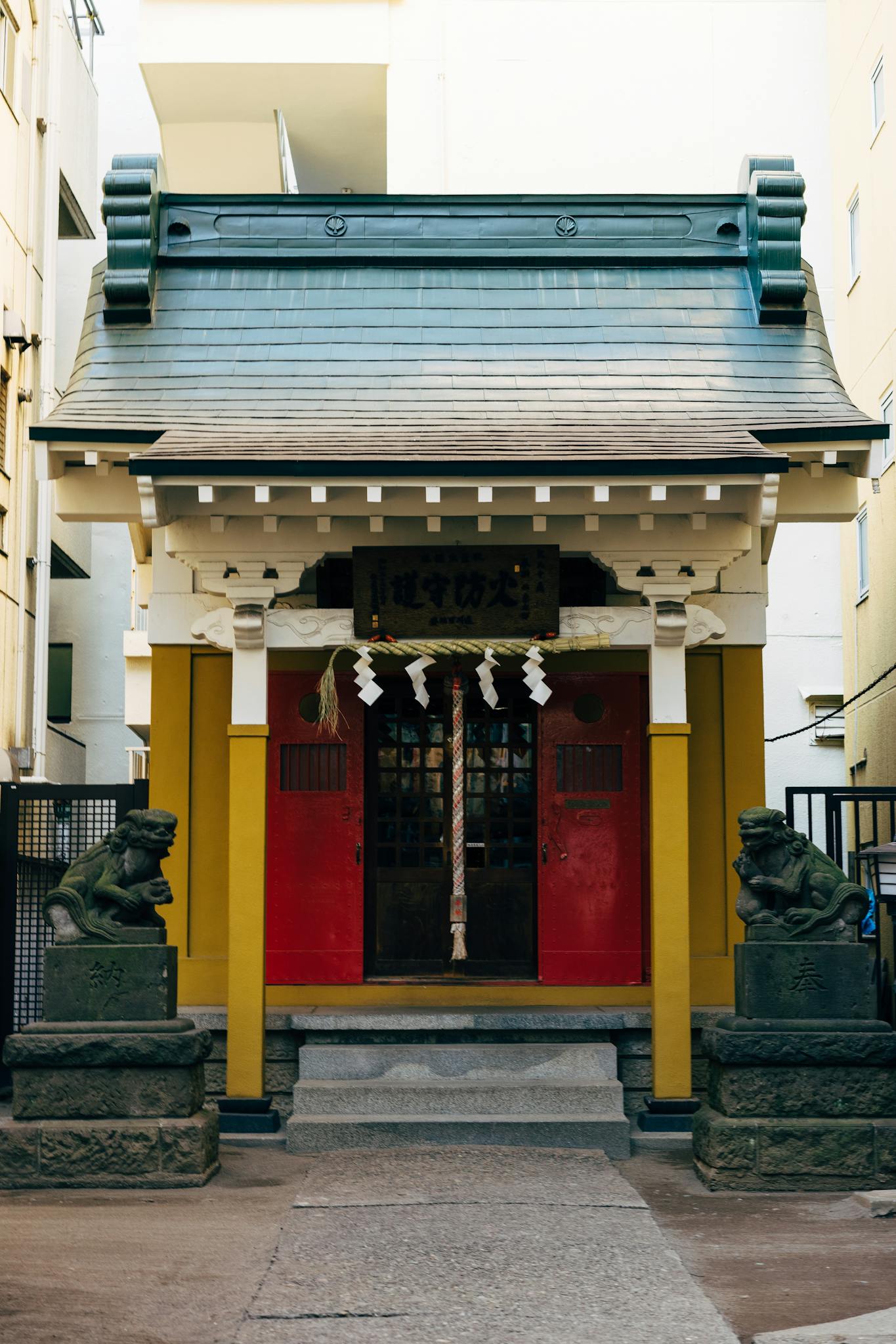 Historic Japanese shrine entrance in Tokyo with decorative statues and vibrant red door.